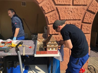 Mitarbeiter der Firma Polygonvatro beim Reinigen eines Modells eines pfälzischen Bauernhauses